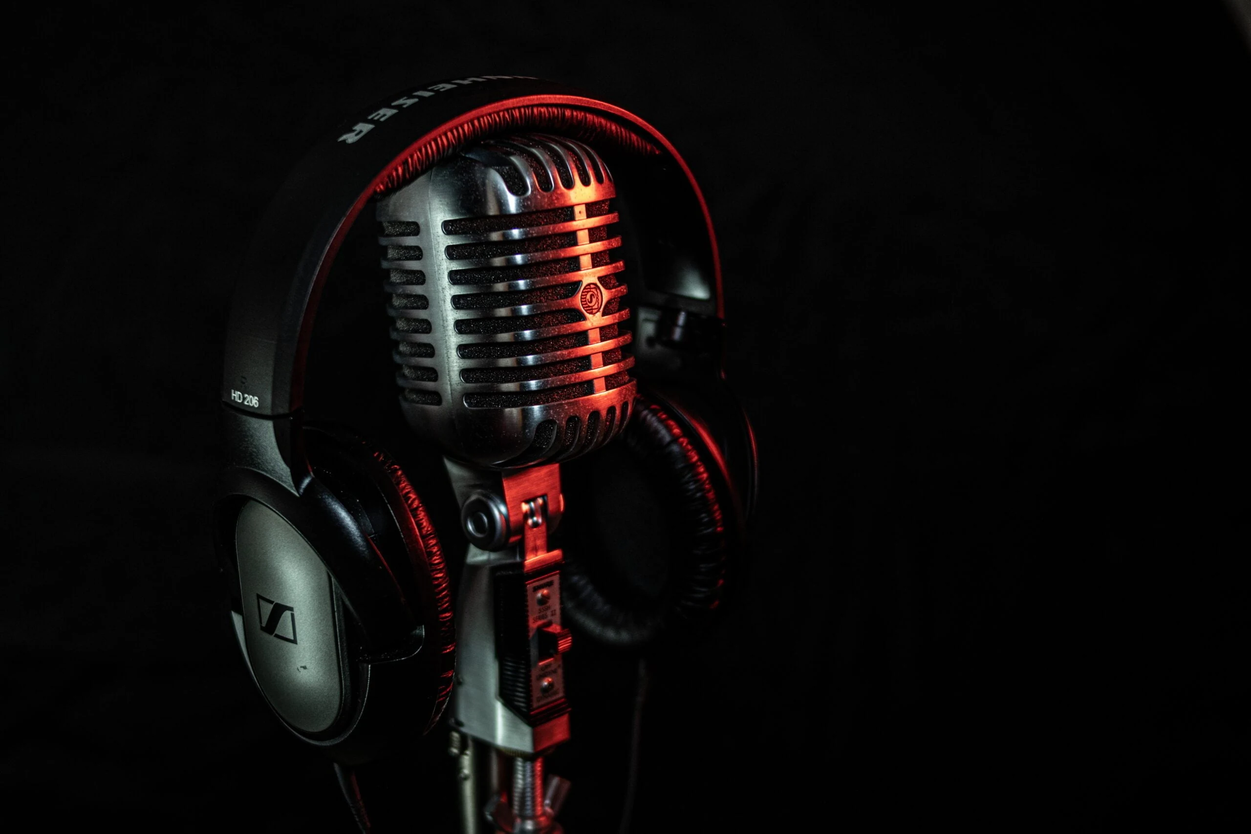 Micrófono y auriculares iluminados en rojo sobre fondo oscuro