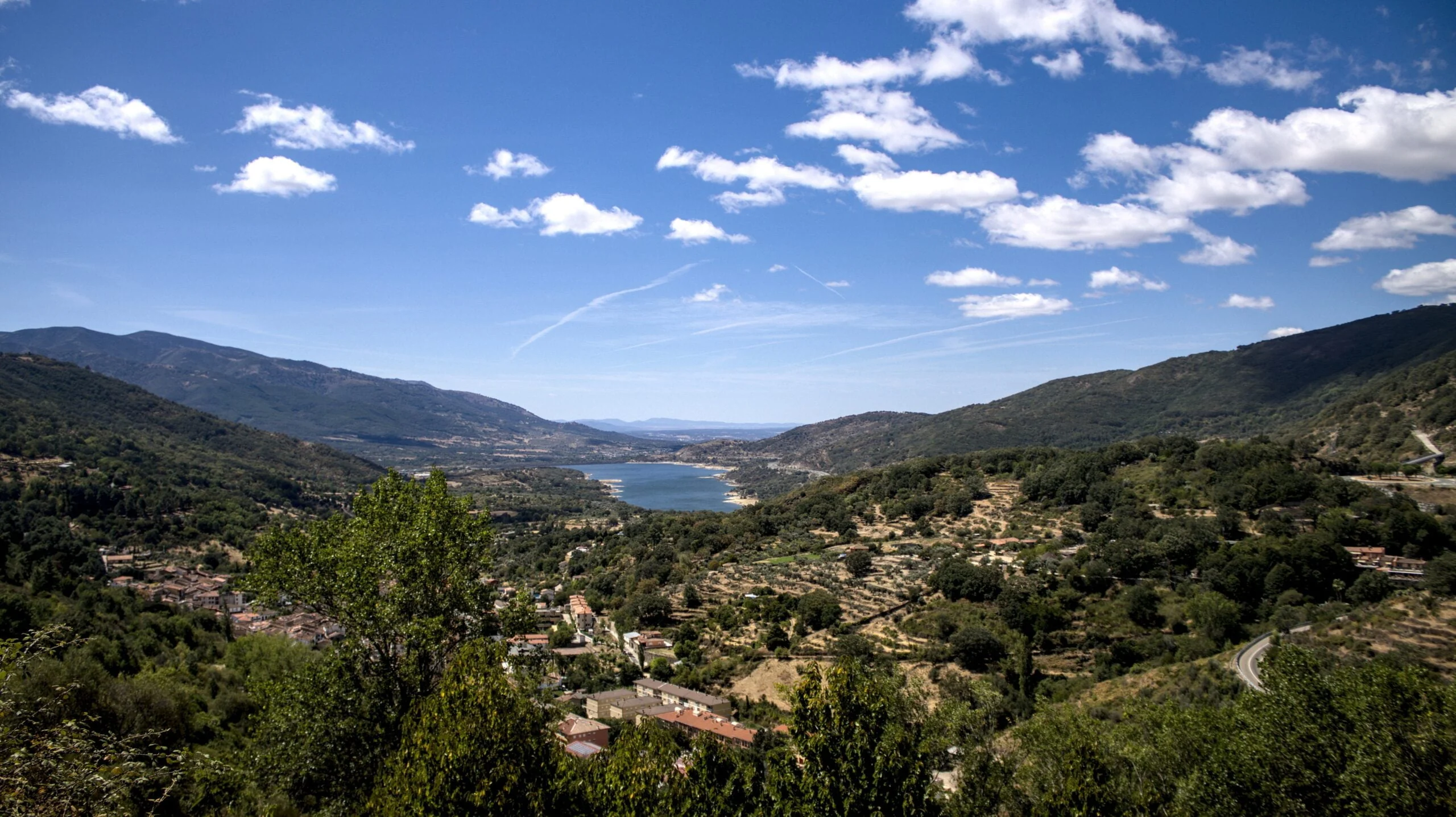 Valle de montaña con un embalse bajo un cielo azul