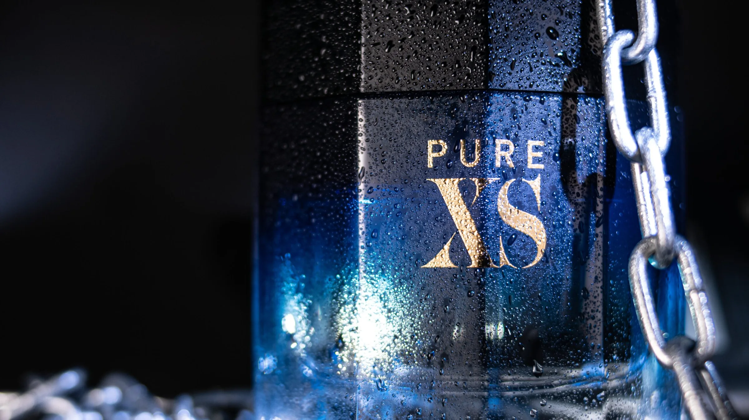 Frasco de perfume iluminado en azul sobre fondo oscuro